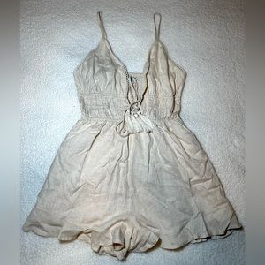 cream color ruffled romper with a tie string in the middle